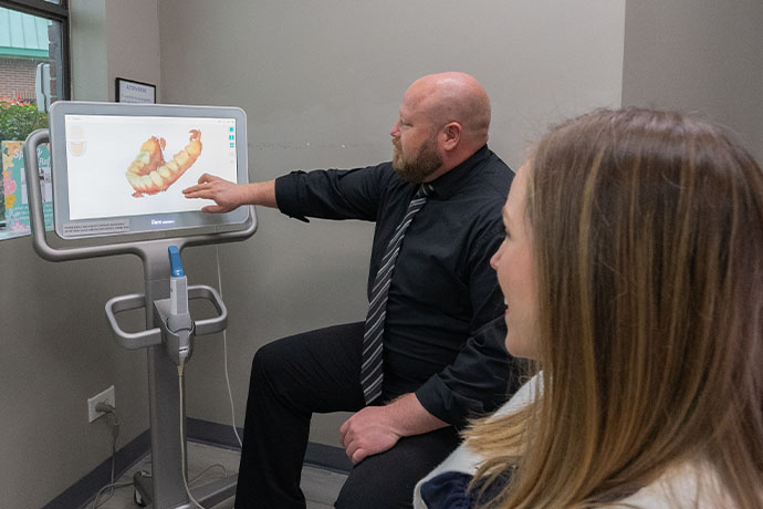 Dr. Jacob A. Burch shows an image of teeth in the monitor to a female patient